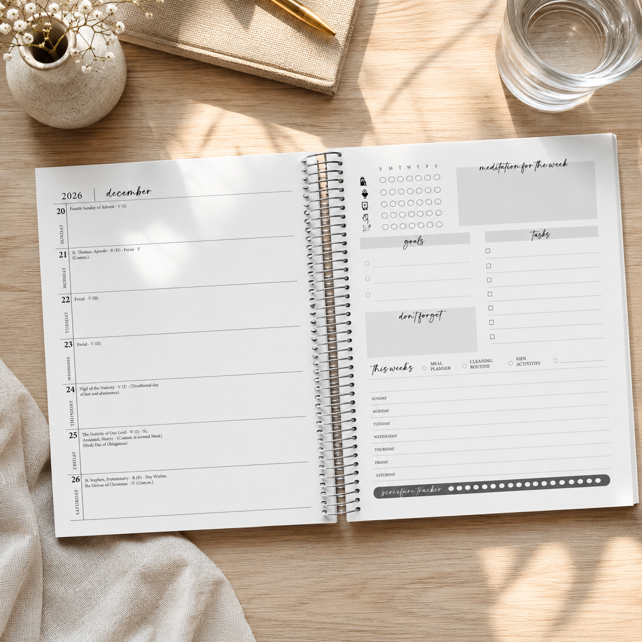 An open spiral-bound planner laid on a light wood desk, showing a weekly calendar layout on the left page and a task/reflective layout on the right page. The planner is styled with a glass of water, a notebook, and a small vase in the background.